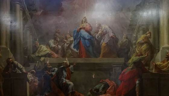 Tongues of fire descend on Mary and the apostles gathered in a great hall