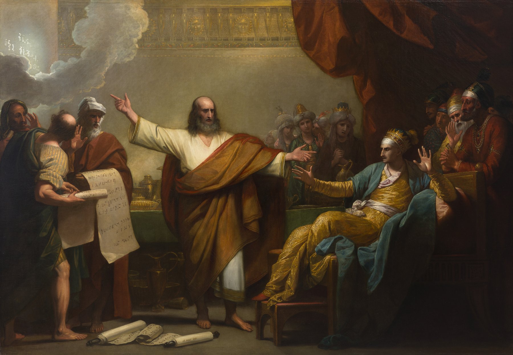 A painting by Benjamin West: in a palace hall, Daniel, bald with a grey beard, in a white robe and a great brownish-red mantle, stretches one arm toward a glowing cloud high on the left and points with the other hand at King Belshazzar. The king, crowned and in gold and blue silks, shrinks back in his chair on the right, his hands raised. Courtiers crowd behind him, and at the left, wise men hold up a long scroll of writing.