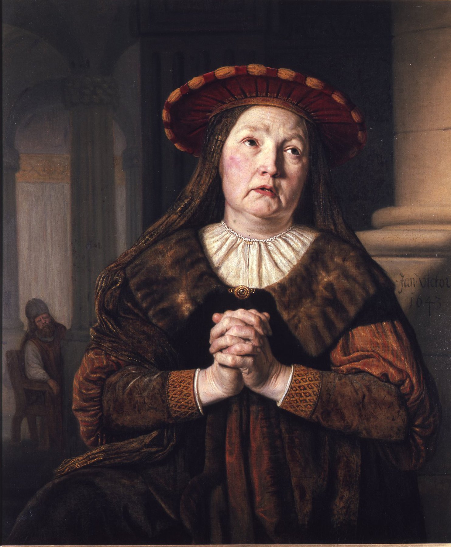 A painting by Jan Victors: Hannah, a woman in middle age, prays with her hands clasped and her eyes raised. She wears a wide red hat trimmed with gold, a white ruff and a fur-trimmed cloak over a brown and orange gown. Behind her, in the shadows of the temple at the left, the old priest Eli sits and watches her.
