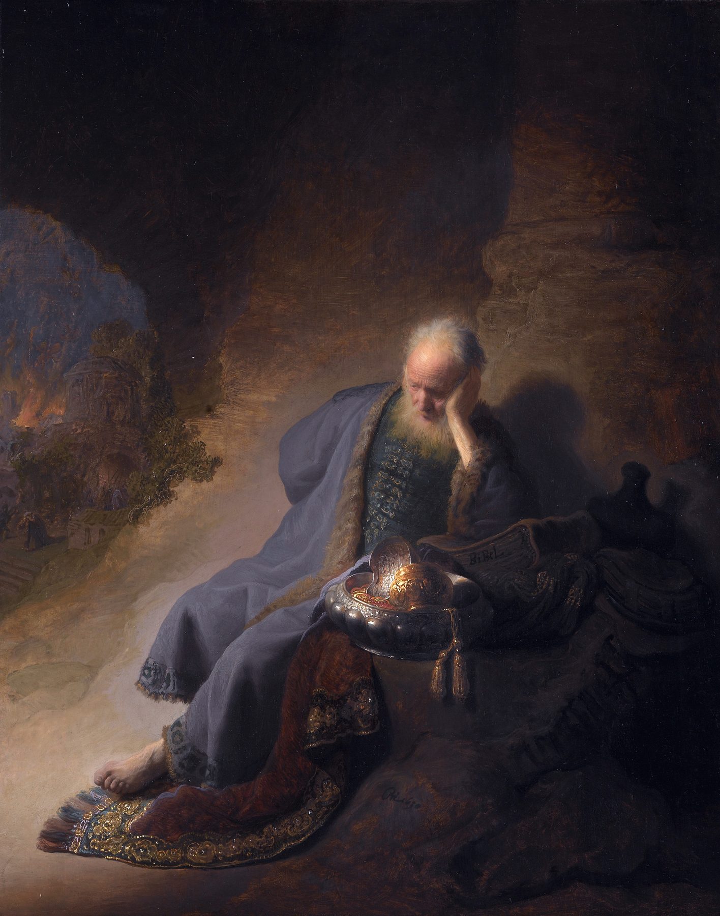 Jeremiah, an old man in a dark robe, sits on a rock with his head resting on his hand beside a pile of gold vessels, while a city burns far off in the dark