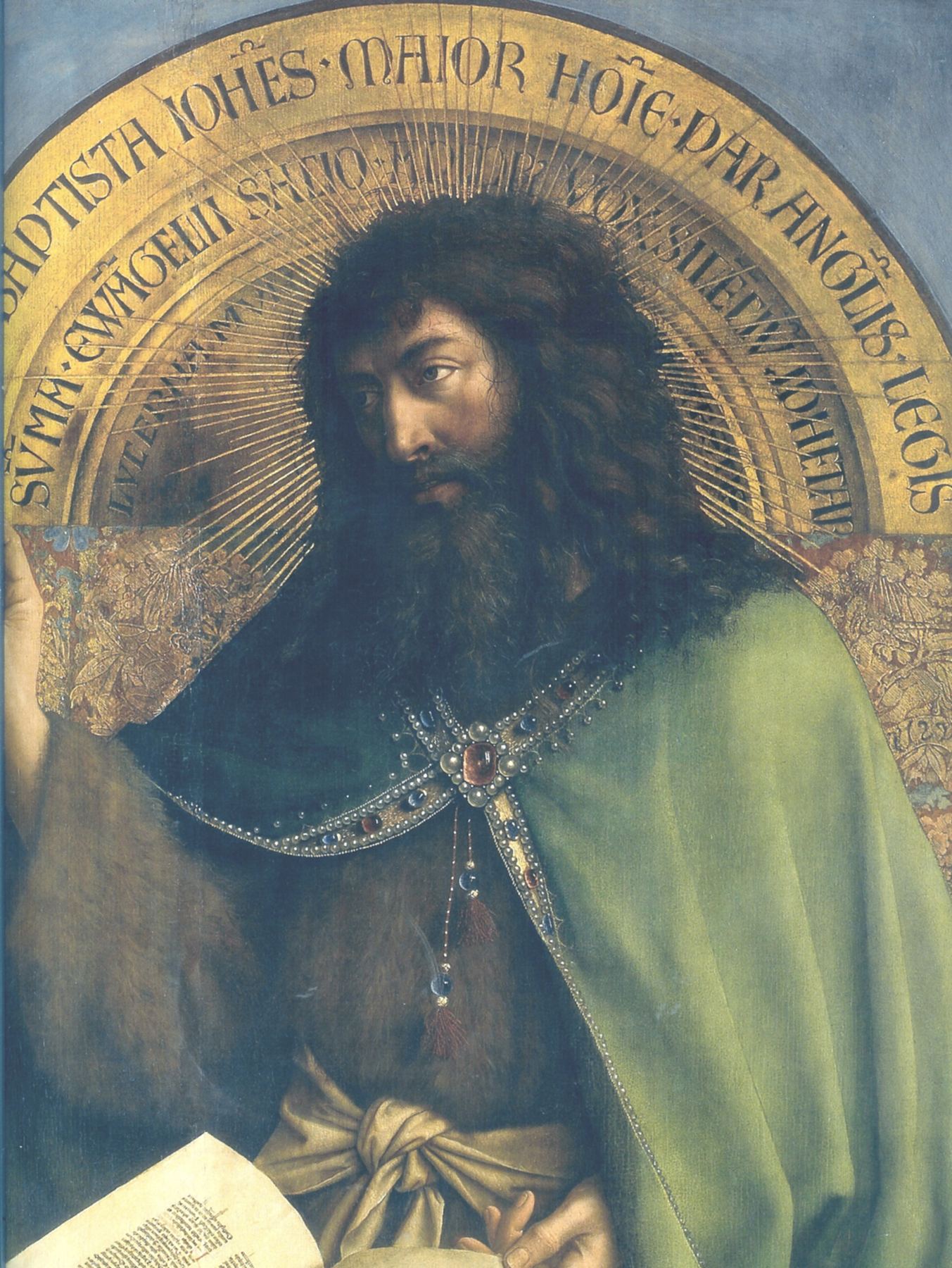 A painting by Jan van Eyck: John the Baptist, with long dark curling hair and a thick dark beard, sits turned a little to one side and looks out calmly. He wears a rough camel-hair garment under a green cloak fastened with a jewelled clasp, and an open book rests on his lap. Behind his head is a gold arch lettered in Latin, with thin gold rays like a halo.