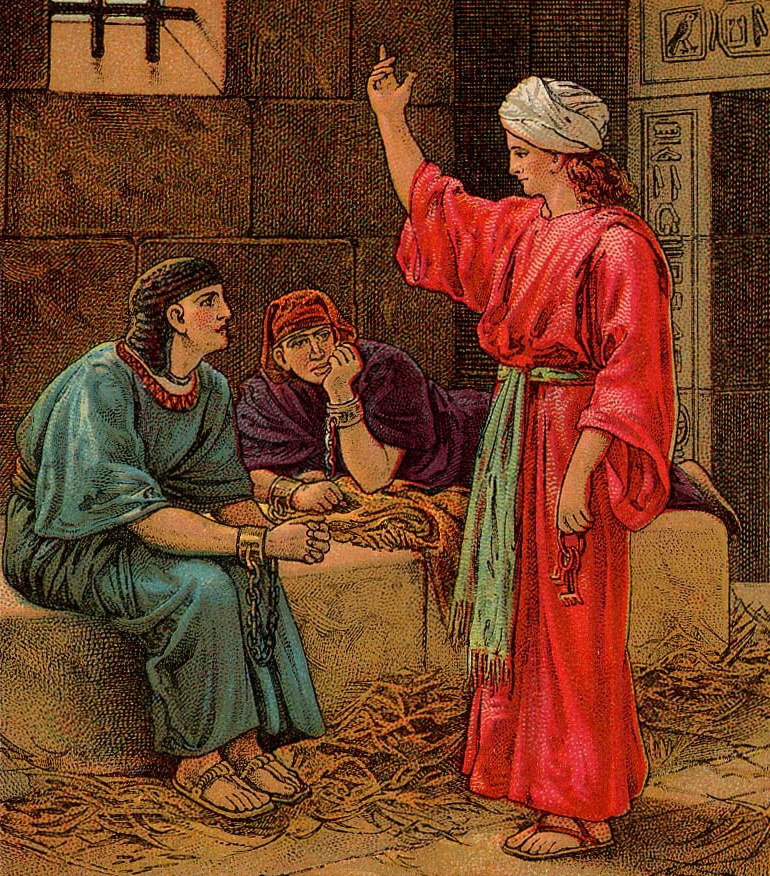 A colour picture card: in a stone prison cell with a barred window and Egyptian carvings, young Joseph, in a red robe, a white turban and a green sash, raises one hand and holds a ring of keys in the other. Before him sit two prisoners in chains, one in a blue robe and a striped headdress, the other in purple, resting his chin on his hand. Straw covers the floor.