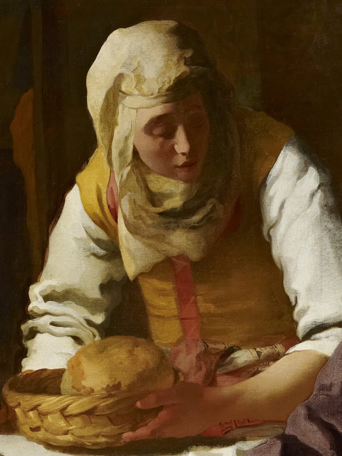 A detail of a painting by Vermeer: Martha, in a white headscarf and a yellow bodice over a white blouse, leans forward to set down a basket of bread