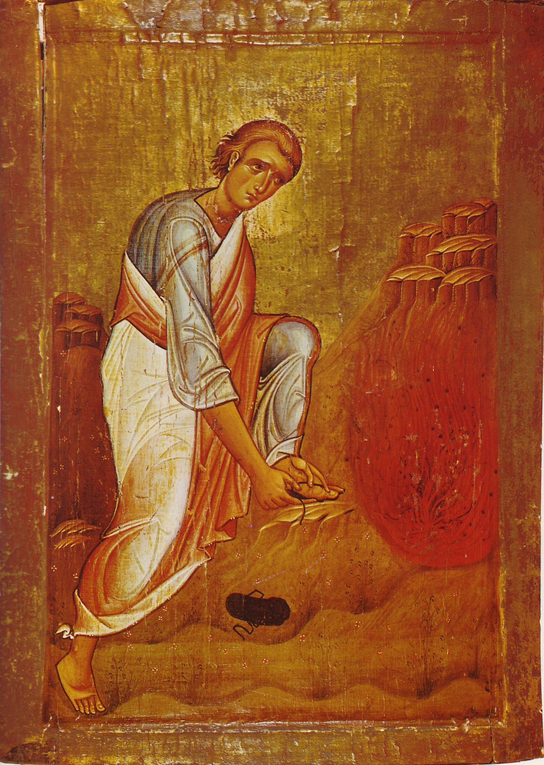 An icon on a gold ground: a young, beardless Moses in a pale blue tunic and a red cloak bends down to untie his sandal. His other sandal lies on the ground behind him. On the right, a bush burns with red flame among brown rocks.