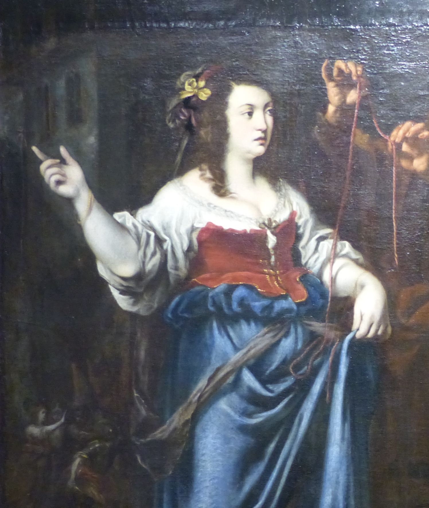 A painting attributed to Matteo Rosselli: Rahab, a young woman with brown hair and a yellow ribbon, stands in a white blouse, a red bodice and a blue skirt, pointing away with one hand. Beside her, the hands of one of the spies hold up a long red cord.