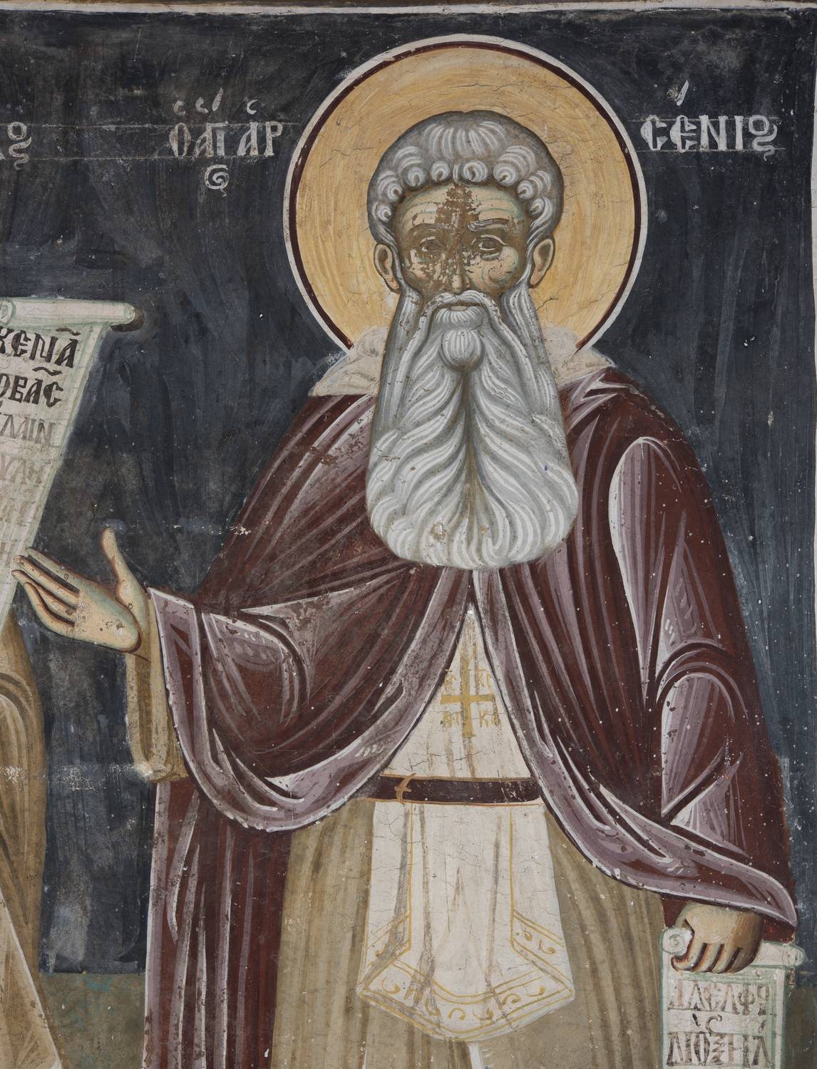 A wall painting: Arsenius, an old monk with thick white hair, a long white beard and a gold halo, in a dark red mantle over a brown habit, holds out his right hand and a small scroll in his left, against a dark blue ground; his name is written in Greek beside his head