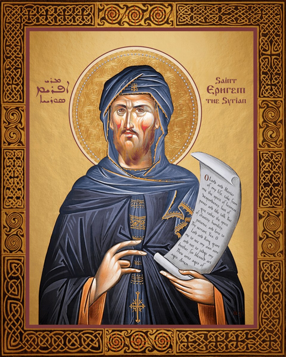 An icon of St Ephrem the Syrian standing in a dark blue hood and robe, one hand raised and the other holding an open scroll, inside a gold frame of interlaced knots