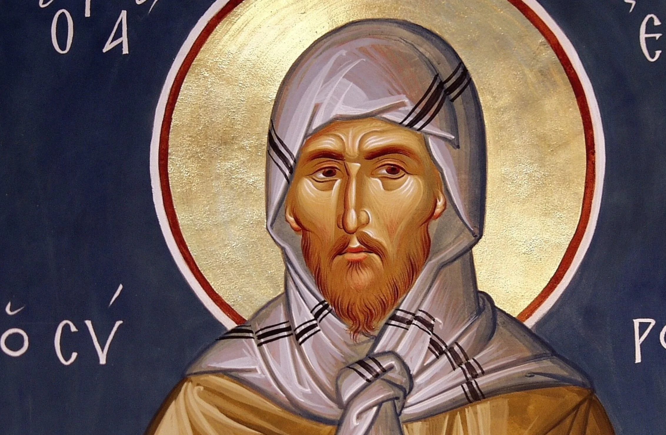 An icon of St Ephrem the Syrian: a monk with a red-brown beard and a grave face, in a grey hood striped with black and knotted at his chest, against a gold halo and a dark blue ground lettered in Greek