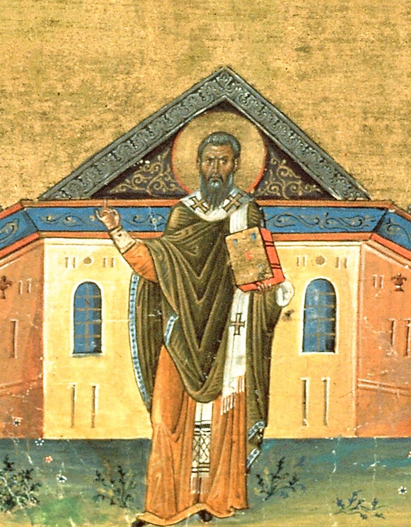 A Byzantine miniature on gold: Gregory, dark-bearded with a halo, stands before a church with arched blue windows. He wears an olive cloak and a white stole with crosses, holds a red-edged Gospel book, and raises his right hand.