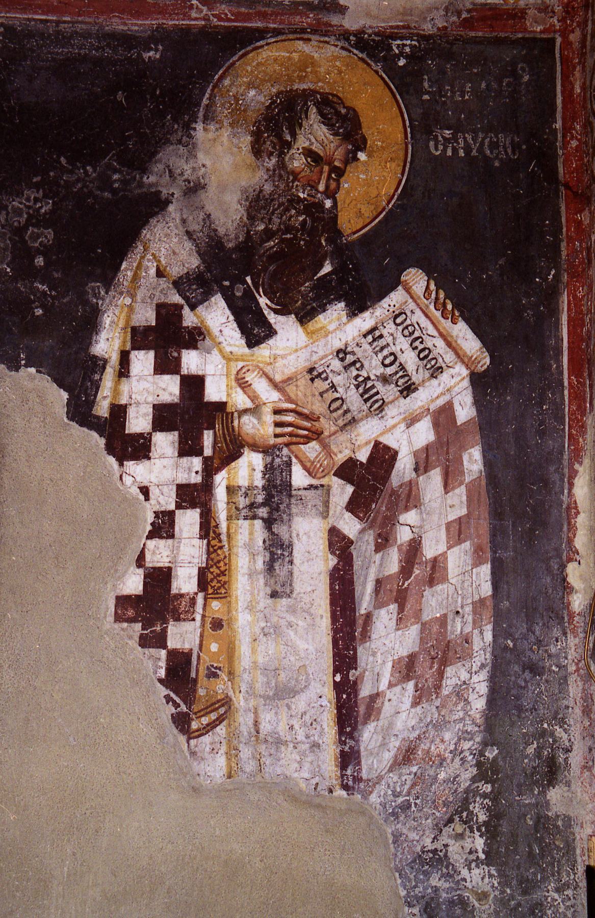 A fresco of Gregory of Nyssa as a bishop with a long dark beard and gold halo, in a white vestment patterned with dark crosses, holding an open scroll