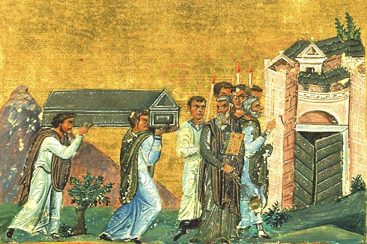 A Byzantine miniature on a gold ground: bishops and clergy in pale robes carry a small gabled reliquary toward the gate of a walled city, led by a man swinging a censer