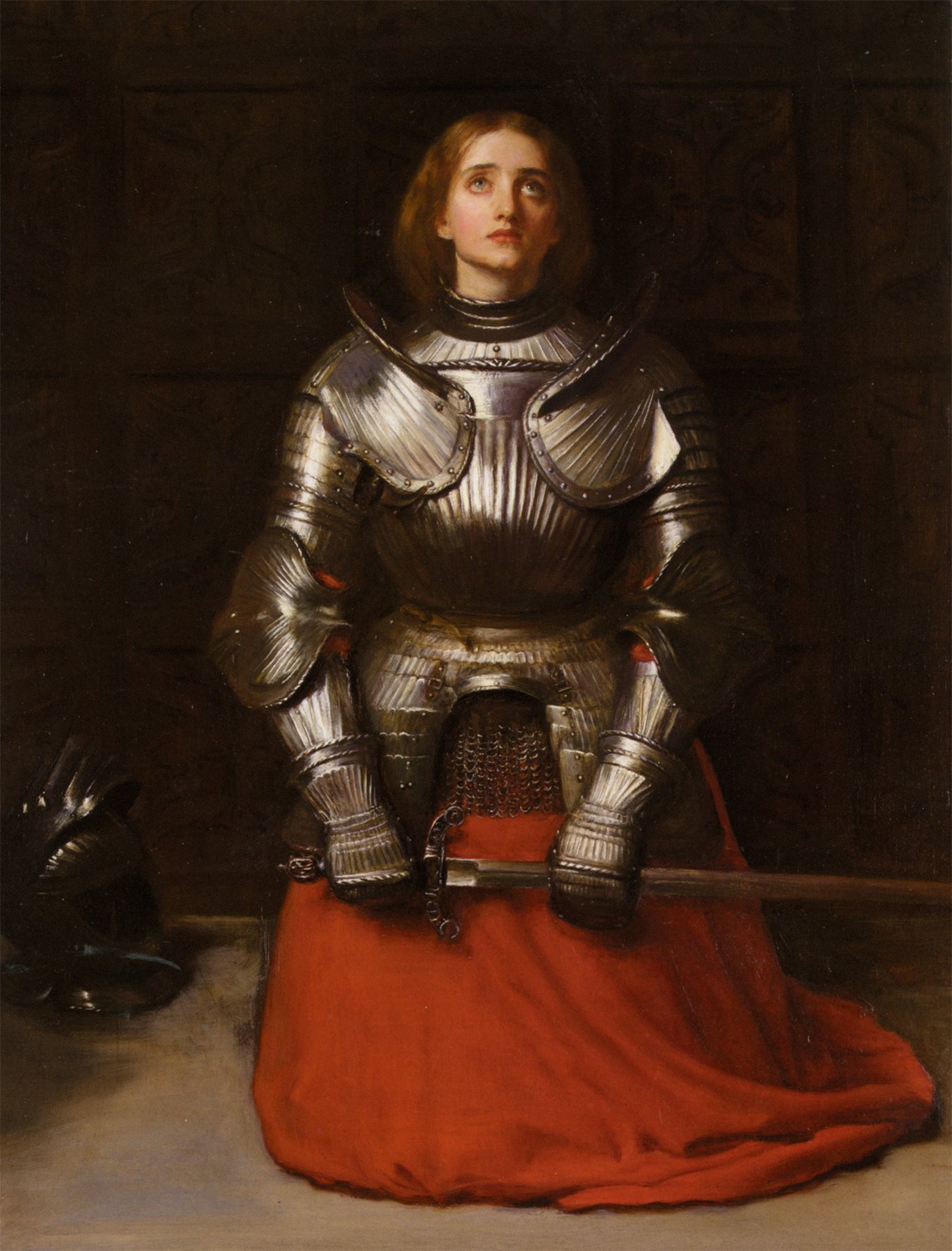 A painting: Joan, a young woman with long reddish-brown hair, kneels in full silver armour in a dark room, her face turned up to heaven and her gauntleted hands resting on a sword across her lap, over a red skirt; her helmet lies on the floor beside her