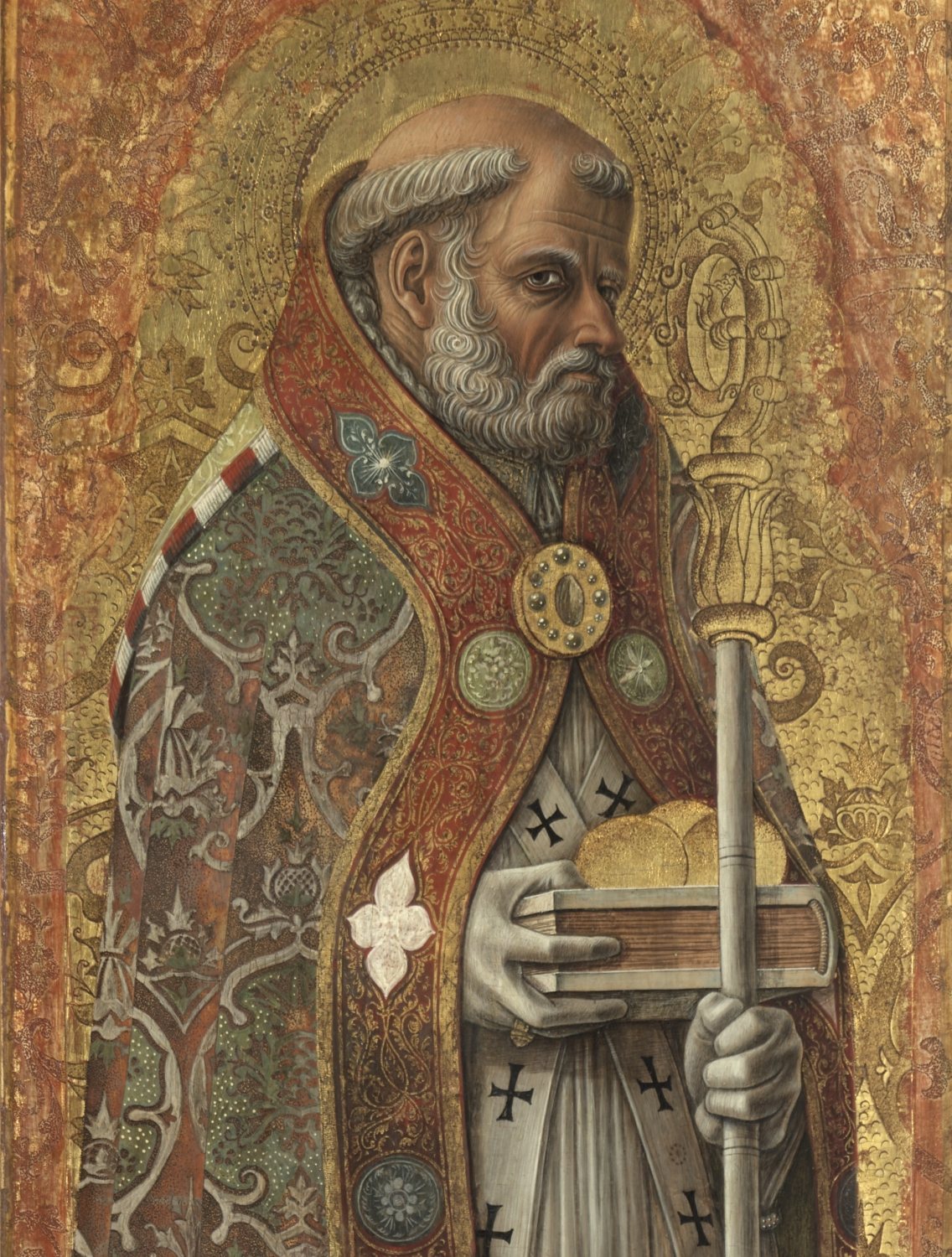 A gilded Italian panel painting: Saint Nicholas, a grey-bearded bishop with a tonsured head, looks down and to the side. He wears a richly embroidered red and green cope over white, holds a crosier, and carries a closed book with three golden balls resting on it.