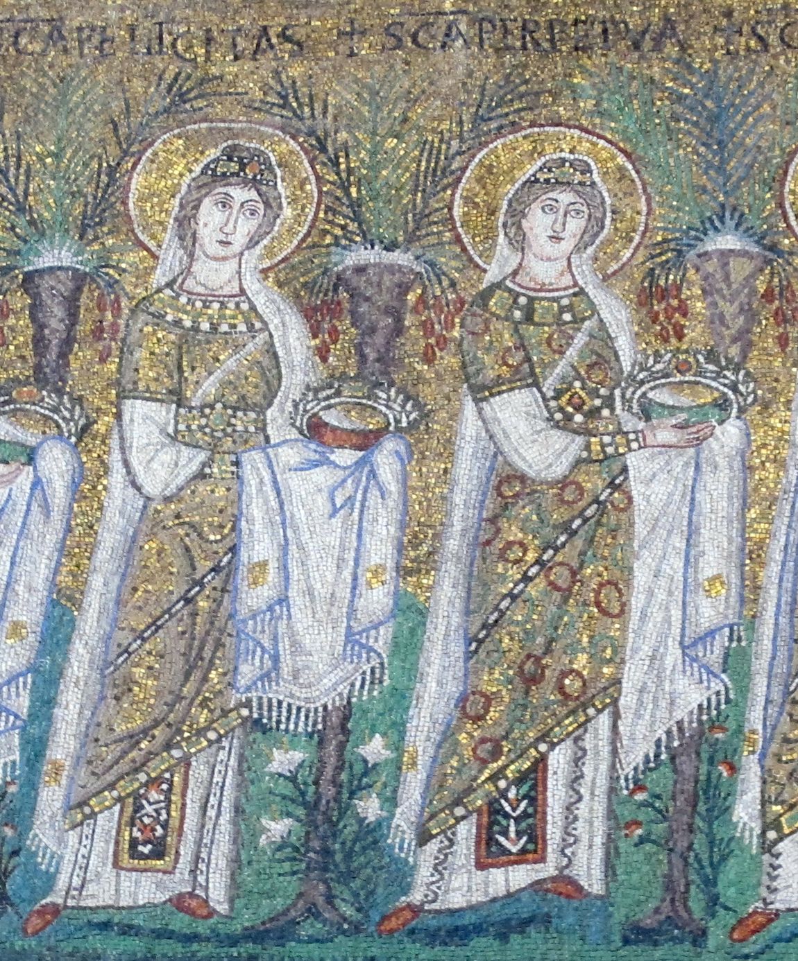 A gold mosaic: two young women saints in jewelled robes and white veils walk side by side between palm trees, each carrying a crown on a white cloth. Their names are lettered above them: SCA FELICITAS and SCA PERPETVA.
