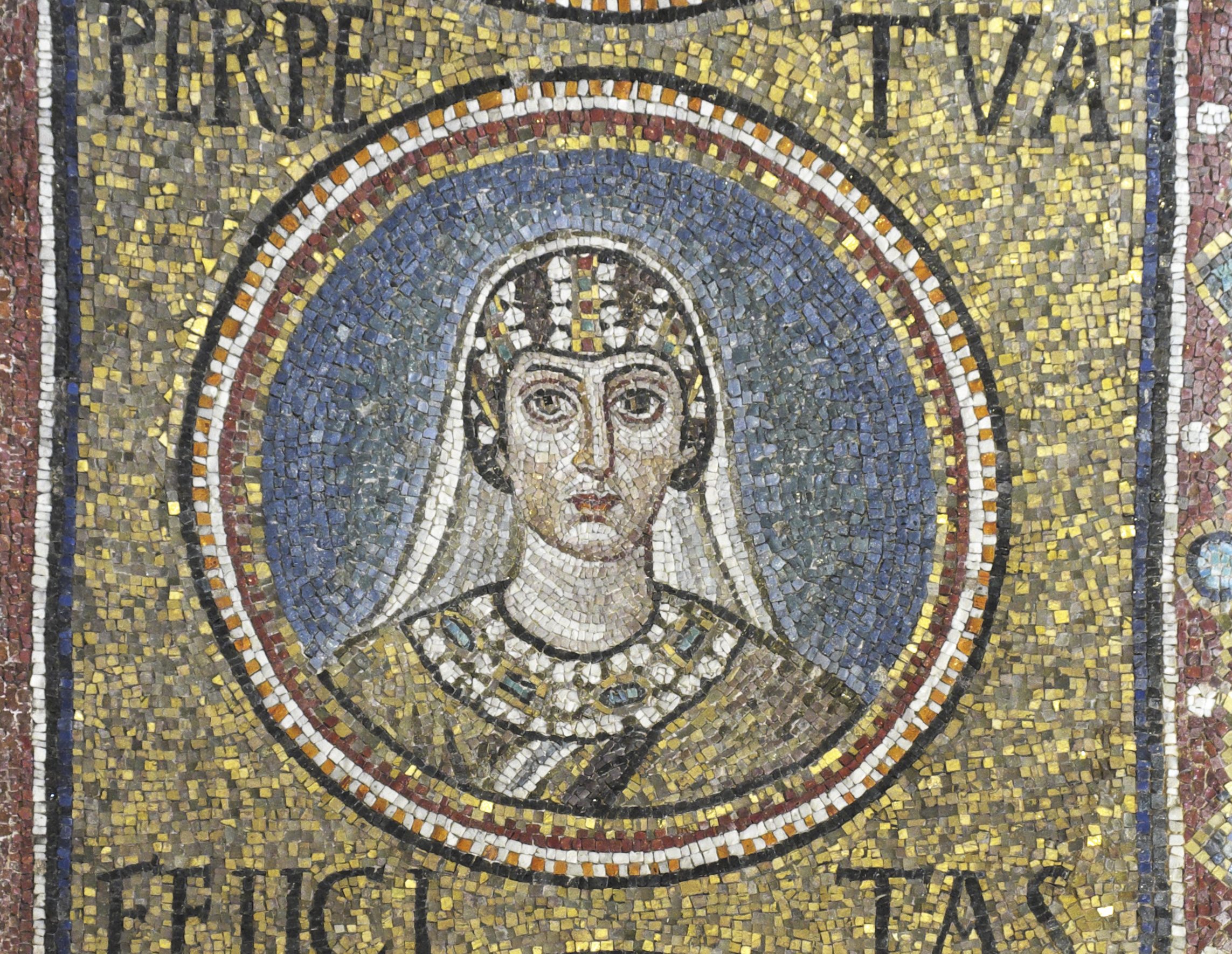 A mosaic medallion of Saint Perpetua: a young woman with large dark eyes, a white veil over her hair, a jewelled band on her head and a jewelled collar, against a blue ground in a gold field. Her name, PERPETVA, is set in the gold above her.